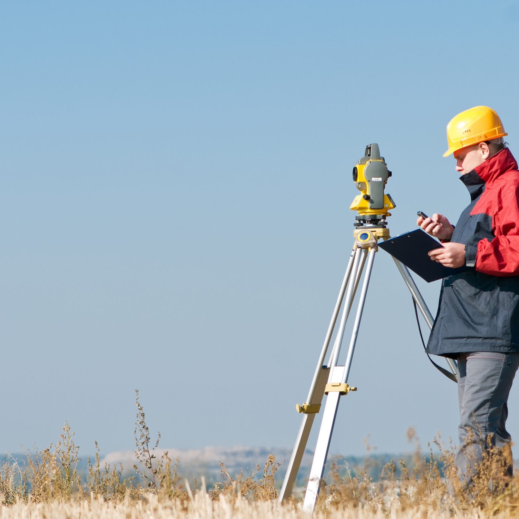 Surveyor worker making measurement in a field with theodolite total station equipment